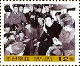 Colnect-2412-452-Kim-smiling-surrounded-by-soldiers.jpg